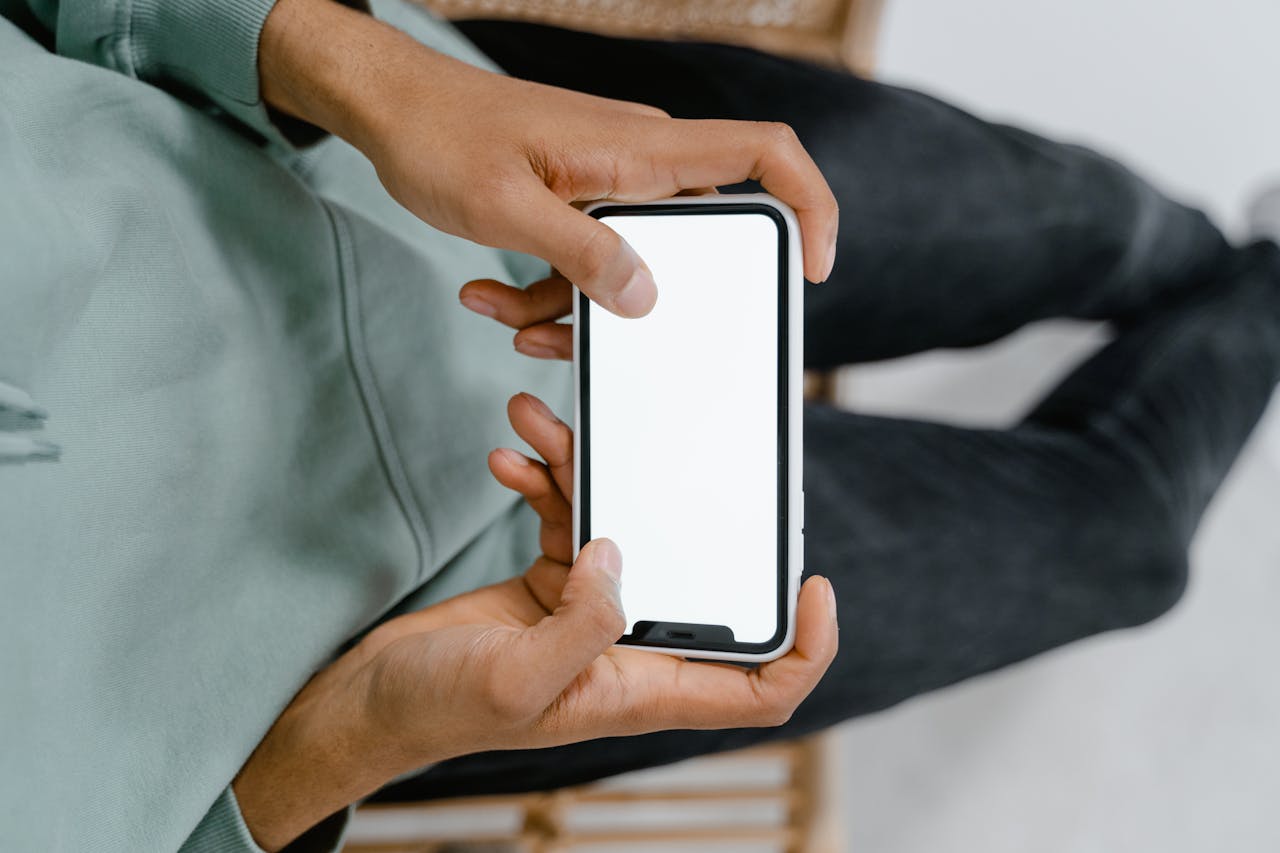 A close-up view of hands holding a smartphone with a blank screen, ideal for digital display mockups.